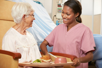 caregiver giving food to her elderly patient